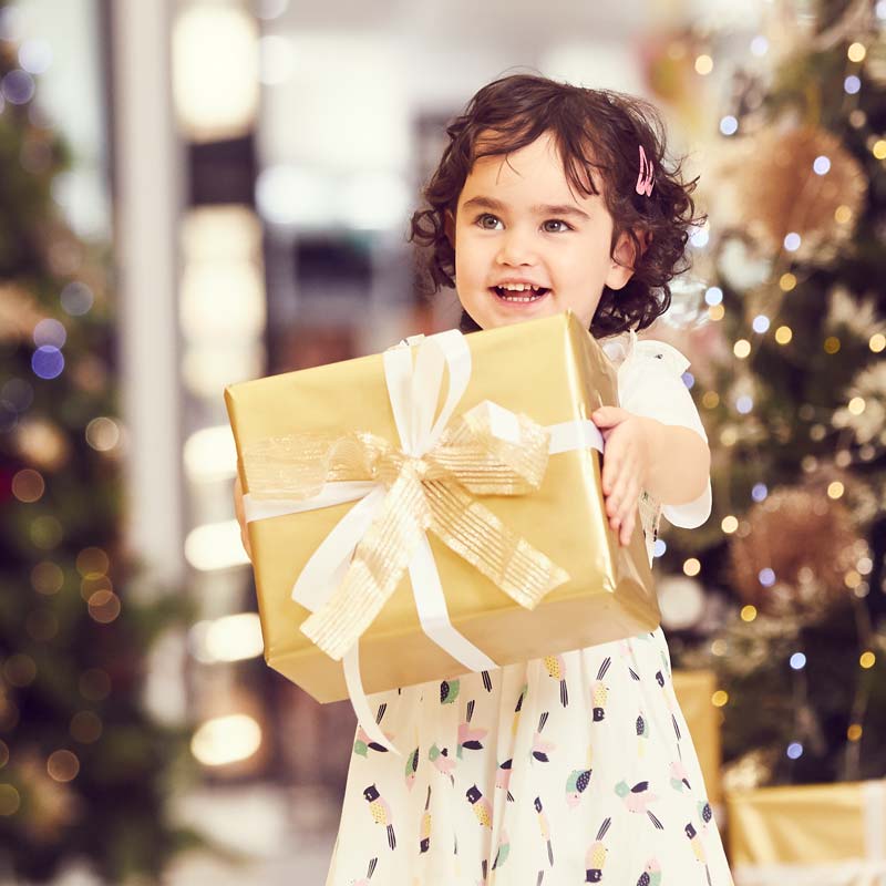 Young girl smiling, holding wrapped Christmas gift