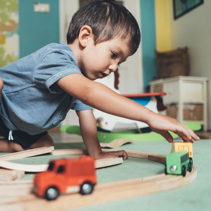 Young boy playing with wooden train set